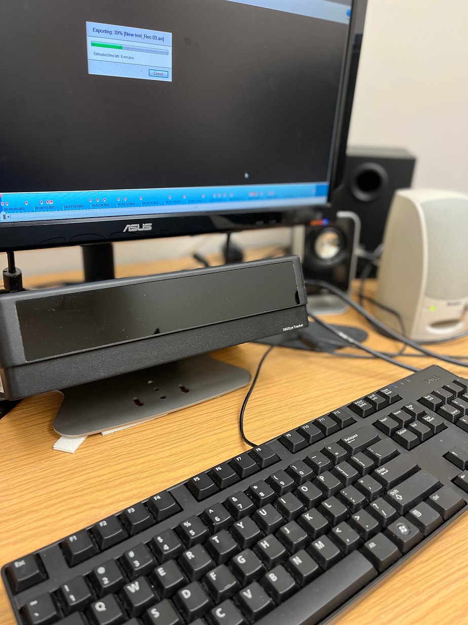 Tobii eye tracker mounted beneath a monitor in the lab, with the eye-tracking software actively exporting a recording